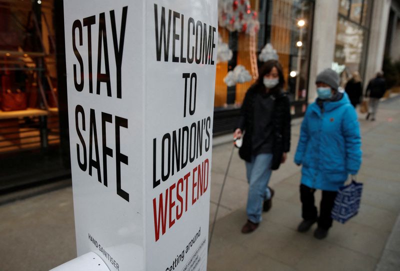 &copy; Reuters. FILE PHOTO: Shoppers walk past a coronavirus related warning sign, amid the coronavirus disease (COVID-19) pandemic in London, Britain, December 11, 2021.  REUTERS/Peter Nicholls