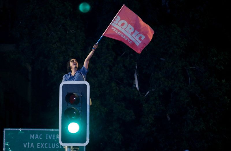 &copy; Reuters. Apoiador do presidente eleito do Chile, Gabriel Boric, comemora vitória com bandeira em semáforo de Santiago
19/12/2021 REUTERS/Rodrigo Garrido