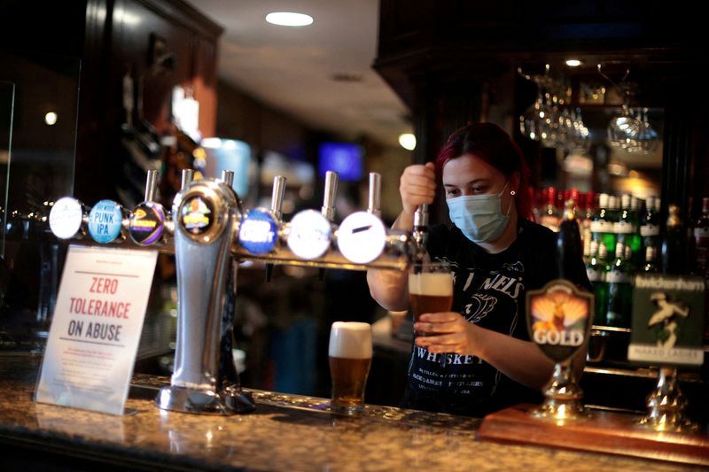 &copy; Reuters. FILE PHOTO: A woman pours beer into a glass at The Fox on the Hill pub in London, Britain, May 17, 2021. REUTERS/Hannah McKay/File Photo