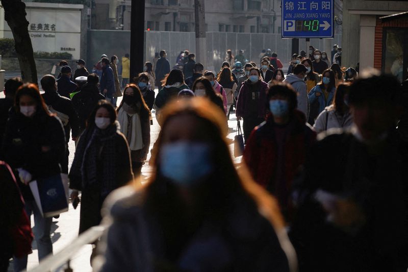 &copy; Reuters. FILE PHOTO: People wearing protective masks walk on a street, following new cases of the coronavirus disease (COVID-19), in Shanghai, China, December 20, 2021. REUTERS/Aly Song/File Photo