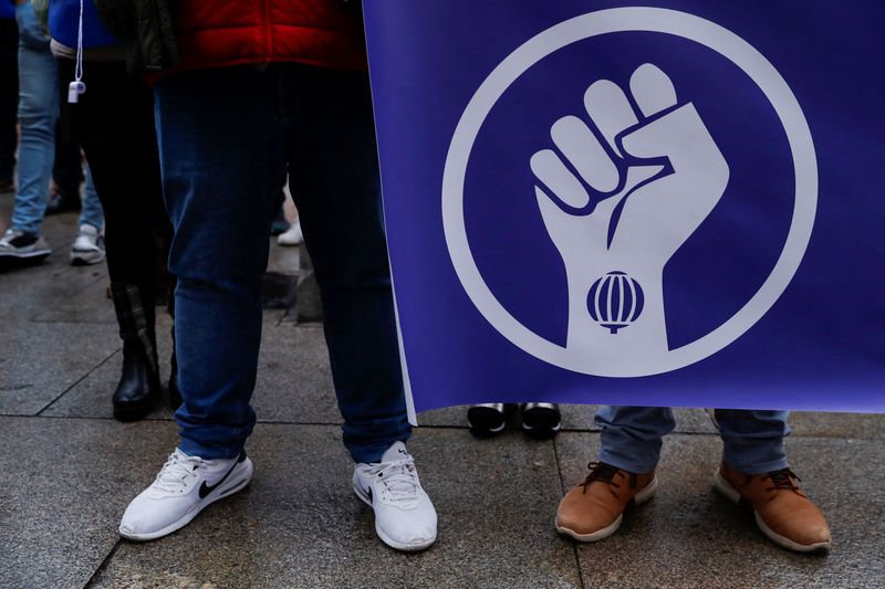 &copy; Reuters. Un grupo de personas con una pancarta que muestra un puño levantado y el logotipo de la Lotería Nacional de España mientras los vendedores de lotería españoles protestan por las supuestas bajas comisiones mientras se celebra el tradicional sorteo de 