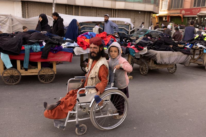 &copy; Reuters. A boy pushes a man's wheelchair on a street in Kabul, Afghanistan, October 22, 2021. REUTERS/Jorge Silva