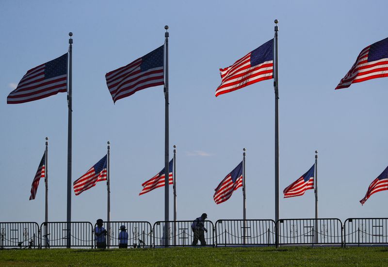 &copy; Reuters. FILE PHOTO: People walk beneath U.S. flags surrounding the Washington monument on the National mall, near the White House in Washington, U.S., November 10, 2020. REUTERS/Tom Brenner