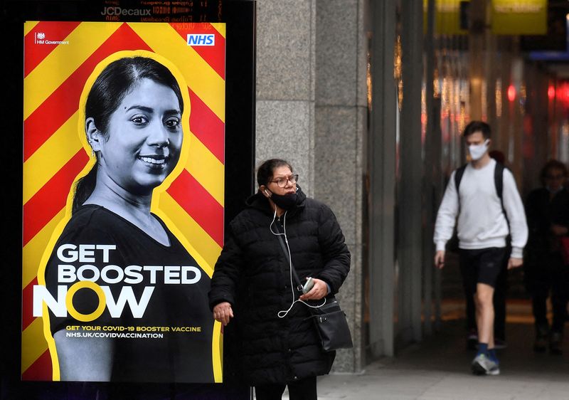 &copy; Reuters. FOTO DE ARCHIVO: Gente pasando ante un anuncio de la campaña sanitaria del Gobierno que anima a recibir una dosis de refuerzo de la vacuna contra el COVID-19, en una parada de autobús, durante la pandemia, en Londres, Reino Unido, 17 de diciembre de 202