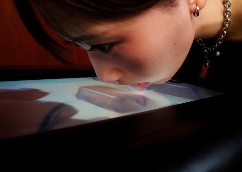 &copy; Reuters. Una estudiante de la Universidad de Meiji prueba un prototipo de pantalla que puede lamerse para detectar sabores como parte de la tecnología de realidad inmersiva en Tokio, Japón. Diciembre 22, 2021.   REUTERS/Kim Kyung-Hoon