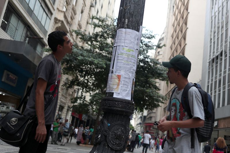 © Reuters. FILE PHOTO: Young men look at job listings posted on a street in downtown Sao Paulo, Brazil April 24, 2019. REUTERS/Amanda Perobelli