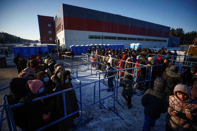 &copy; Reuters. FOTO DE ARCHIVO: Un grupo de personas hace cola para recibir alimentos en el centro de transportes y logística Bruzgi próximo a la frontera entre Bielorrusia y Polonia, en la región de Grozno, Bielorrusia, el 22 de diciembre de 2021. REUTERS/Maxim Shem