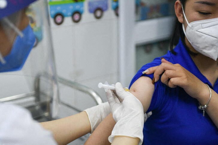 &copy; Reuters. 　１２月２４日、ベトナム保健省は、来年３月末までに全ての成人を対象に新型コロナウイルスワクチンのブースター接種を実施する目標を掲げた。写真は３月、ワクチン接種を受ける人。