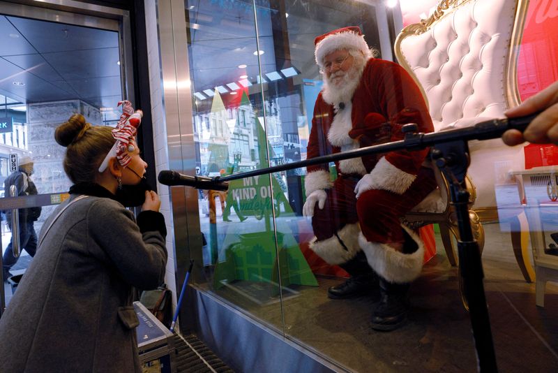 &copy; Reuters. Imagen de archivo de Brielle Peare, de seis años, usando un micrófono para hablar con un hombre disfrazado de Santa Claus, quien está sentado en el escaparate de una tienda detrás de una ventana de vidrio como medida para evitar la propagación del CO