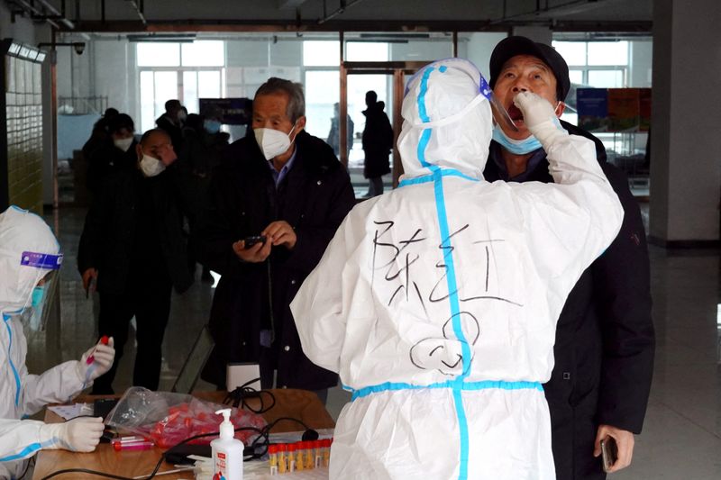 © Reuters. A medical worker in protective suit collects a swab sample from a man for nucleic acid testing at a residential compound, during another round of mass testing following the coronavirus disease (COVID-19) outbreak in Xian, Shaanxi province, China December 27, 2021. cnsphoto via REUTERS 