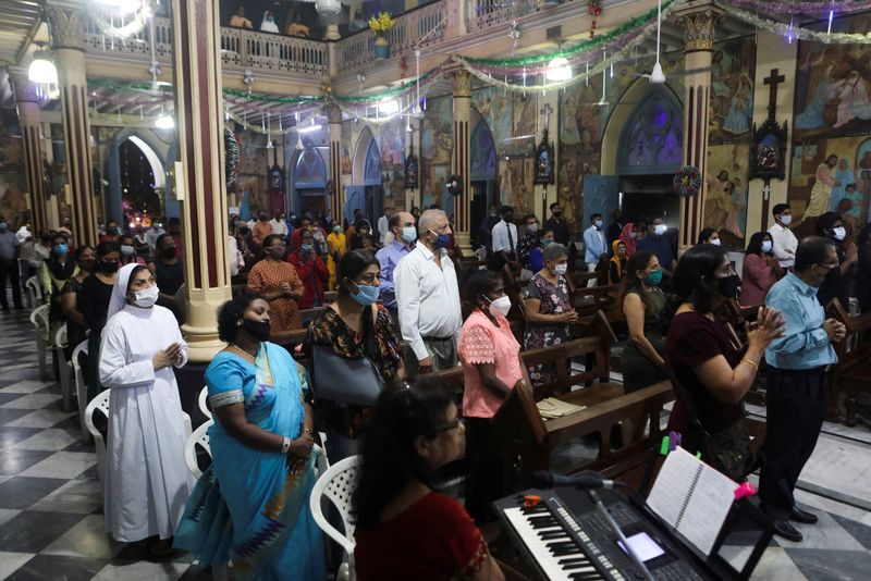 © Reuters. أشخاص يحضرون قداسا احتفالا بليلة عيد الميلاد في مومباي في صورة من أرشيف رويترز. 