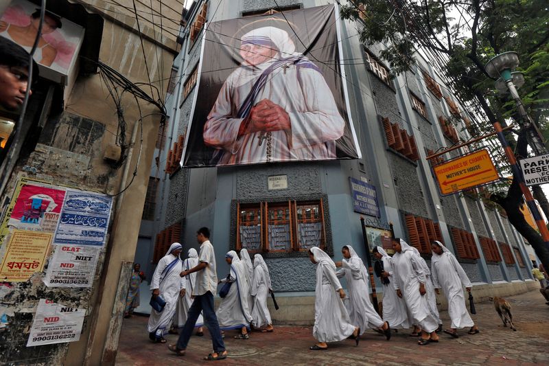 © Reuters. FILE PHOTO: Nuns belonging to the global Missionaries of Charity, walk past a large banner of Mother Teresa ahead of her canonisation ceremony, in Kolkata, India September 3, 2016. REUTERS/Rupak De Chowdhuri