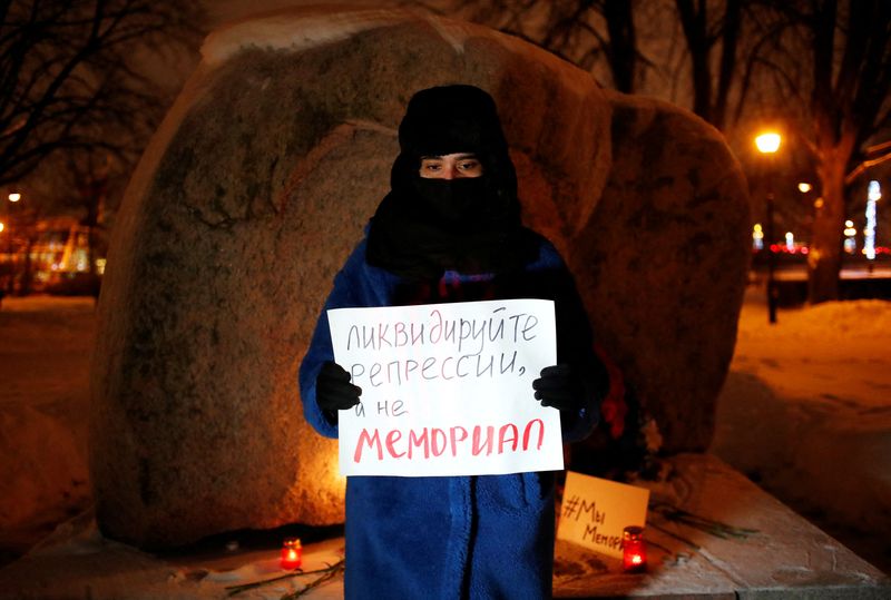 © Reuters. A supporter of the human rights group International Memorial stands with a placard at the Solovetsky Stone memorial after Russia's Supreme Court ruled that International Memorial must be liquidated for breaking the law on foreign agents, in Saint Peterburg, Russia December 28, 2021. The placard reads: 