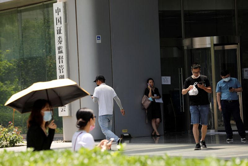 &copy; Reuters. FILE PHOTO: People walk past the China Securities Regulatory Commission (CSRC) sign at its building on the Financial Street in Beijing, China July 9, 2021. REUTERS/Tingshu Wang