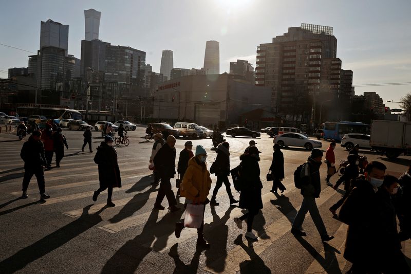 © Reuters. FILE PHOTO: People cross a street during morning rush hour in front of the skyline of the central business district (CBD) in Beijing, China December 15, 2020. REUTERS/Thomas Peter