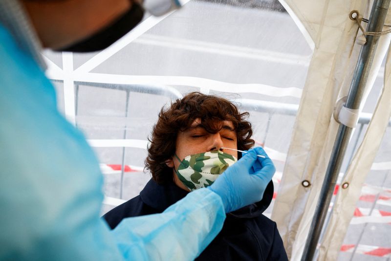 &copy; Reuters. ロイターの算出によると、世界の新型コロナウイルス新規感染者が２２─２８日の平均で１日当たり約９０万人と、過去最多を記録した。１２月２９日、ローマで撮影（２０２１年　ロイタ