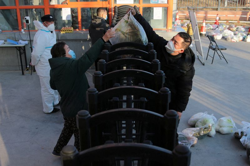 &copy; Reuters. A worker delivers food supplies to residents at a residential compound under lockdown following the coronavirus disease (COVID-19) outbreak in Xian, Shaanxi province, China December 29, 2021. cnsphoto via REUTERS