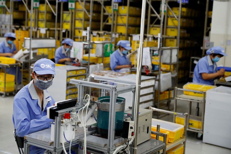 © Reuters. FILE PHOTO: Employees wearing face masks work at a factory of the component maker SMC during a government organised tour of its facility following the outbreak of the coronavirus disease (COVID-19), in Beijing, China May 13, 2020. REUTERS/Thomas Peter