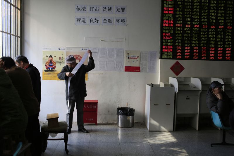 &copy; Reuters. An investor looks at credential receipts after a transaction at a brokerage in Shanghai December 22, 2014. China stocks closed up on Monday in volatile trade as electrical utilities rose and banks spiked, while a slump in small-cap shares limited some gai