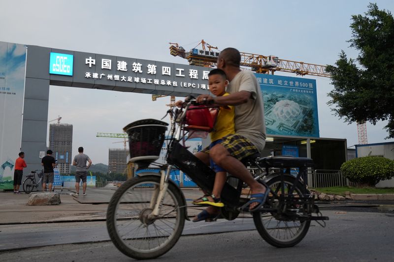© Reuters. Unas personas pasan en bicicleta por delante de las obras de construcción del Guangzhou Evergrande Soccer Stadium, un nuevo estadio para el Guangzhou FC desarrollado por China Evergrande Group, en Guangzhou, provincia de Guangdong, China, 26 de septiembre de 2021. REUTERS/Aly Song