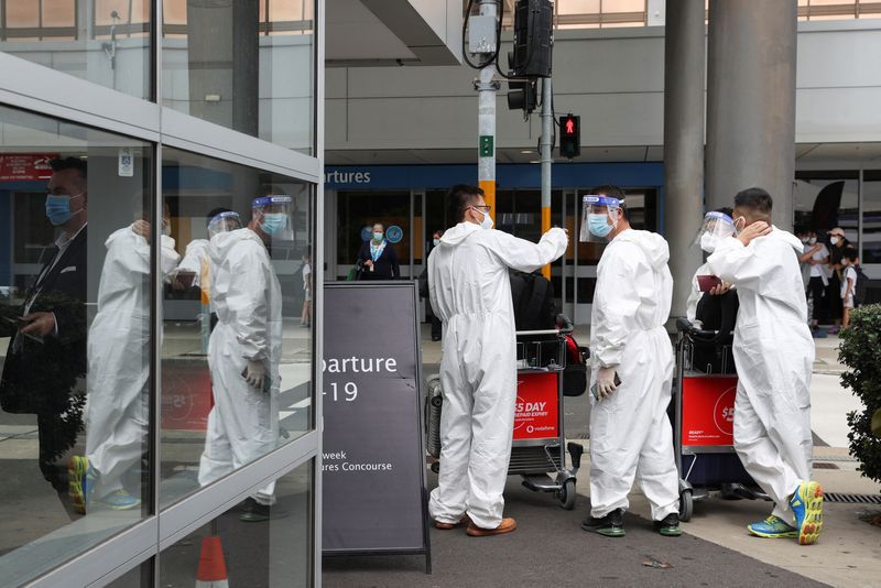 &copy; Reuters. FILE PHOTO: Travellers wear personal protective equipment outside the international terminal at Sydney Airport, as countries react to the new coronavirus Omicron variant amid the coronavirus disease (COVID-19) pandemic, in Sydney, Australia, November 29, 