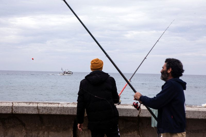 &copy; Reuters. Israeli fishermen stand by the shore of the Mediterranean Sea following rockets fired by Palestinian militants in Gaza, causing an explosion off the shore of Tel Aviv, according to Israel's military, in Tel Aviv, Israel January 1, 2022. REUTERS/Nir Elias