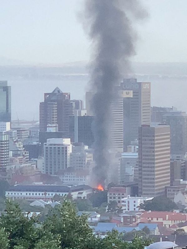 © Reuters. دخان يتصاعد من مبنى محترق في كيب تاون بجنوب أفريفيا يوم الأحد. صورة لرويترز من مواقع التواصل الاجتماعي. (يحظر إعادة بيع أو الاحتفاظ بالصورة في الأرشيف).