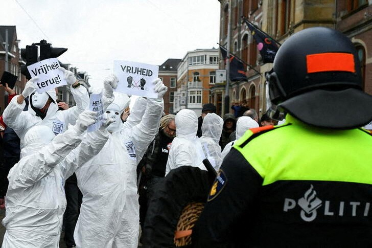 &copy; Reuters. Un manifestante muestra un cartel con la palabra "Libertad" ante un policía durante una manifestación contra las medidas para frenar al coronavirus en Ámsterdam, Holanda. 2 enero 2022. REUTERS/Piroschka van de Wouw