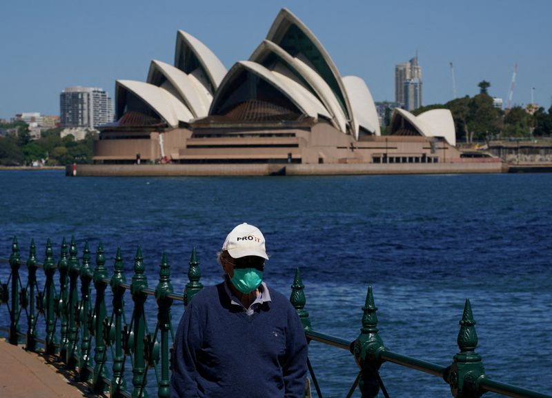 &copy; Reuters. FILE PHOTO: A person wearing a face mask walks along the harbour waterfront across from the Sydney Opera House during a lockdown to curb the spread of coronavirus disease (COVID-19) in Sydney, Australia, October 6, 2021. REUTERS/Loren Elliott