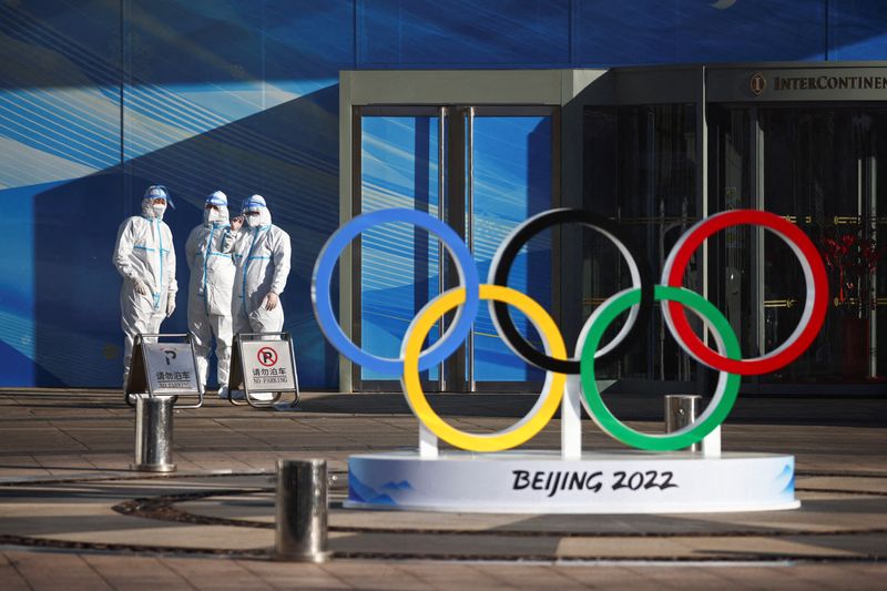 &copy; Reuters. FILE PHOTO: Workers in PPE stand next to the Olympic rings inside the closed loop area near the National Stadium, or the Bird's Nest, where the opening and closing ceremonies of Beijing 2022 Winter Olympics will be held, in Beijing, China December 30, 202
