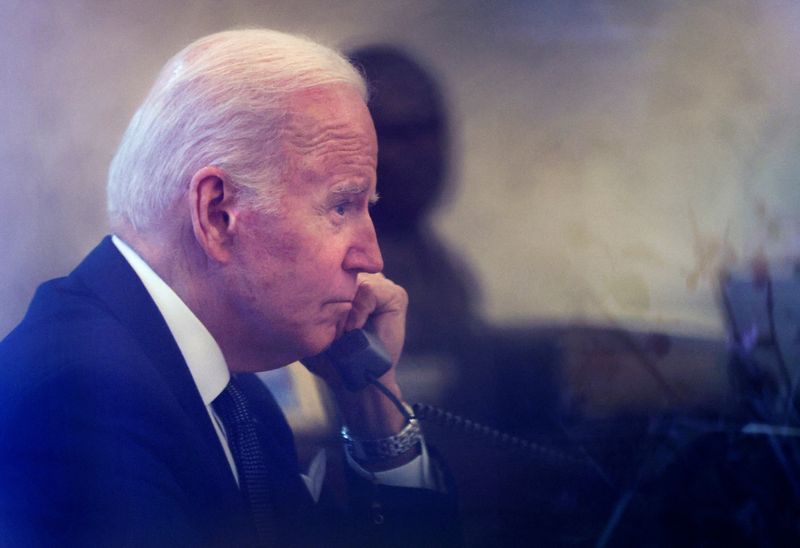 &copy; Reuters. Il presidente degli Stati Uniti Joe Biden fotografato attraverso una porta di vetro nello Studio Ovale mentre parla al telefono con il presidente dell'Ucraina Volodymyr Zelenskiy alla Casa Bianca a Washington, negli Stati Uniti, 9 dicembre 2021. REUTERS/L