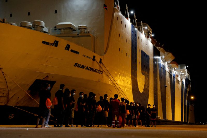 © Reuters. مهاجرون يسيرون باتجاه سفينة للخضوع للحجر الصحي عقب نزولهم من على متن سفينة سي-ووتش 3 الألمانية في تراباني بجزيرة صقلية الايطالية يوم 7 أغسطس آب 2021. تصوير:رويترز.