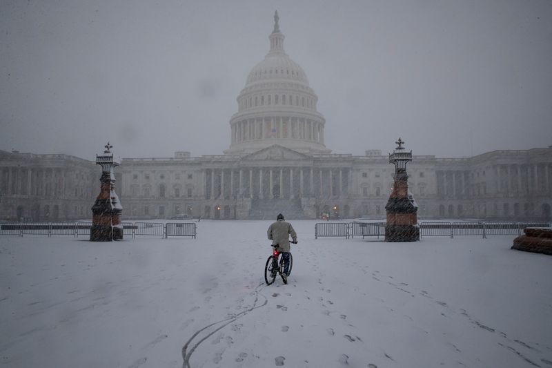 &copy; Reuters. A bicyclist rides along the East Front Plaza during a snow storm on Capitol Hill in Washington, U.S., January 3, 2022. REUTERS/Tom Brenner