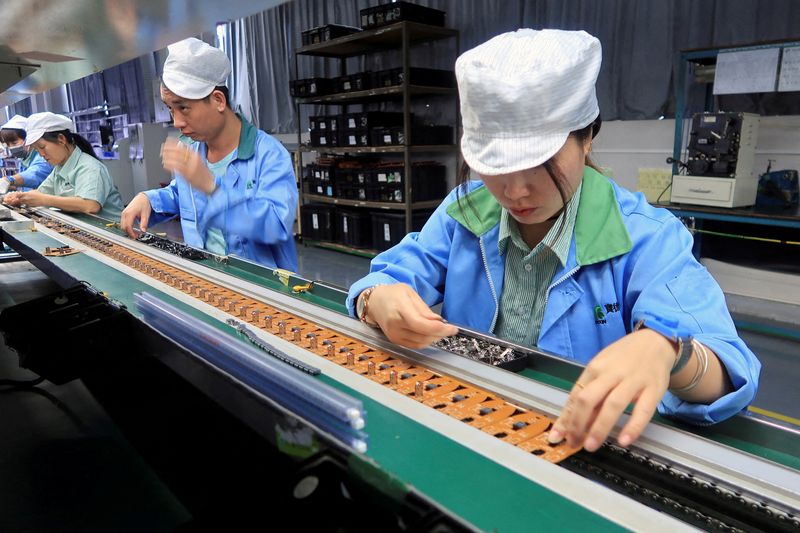 &copy; Reuters. FILE PHOTO: Employees work on the production line of mobile gaming controllers for U.S. company T2M, at a factory in Dongguan, Guangdong Province, China December 7, 2021. REUTERS/David Kirton