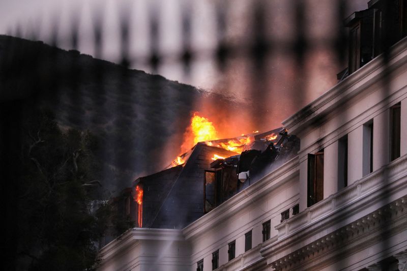 &copy; Reuters. Flames and smoke rise over the roof of the National Assembly building as the fire at the parliament flared up again, in Cape Town, South Africa, January 3, 2022. Picture taken through a fence. REUTERS/Sumaya Hisham