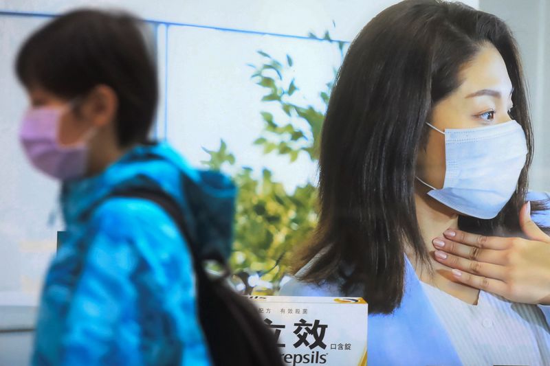 &copy; Reuters. A pedestrian walks past a medicine advertisement with a woman wearing a face mask, in Taipei, Taiwan, November 30, 2021. REUTERS/I-Hwa Cheng/Files