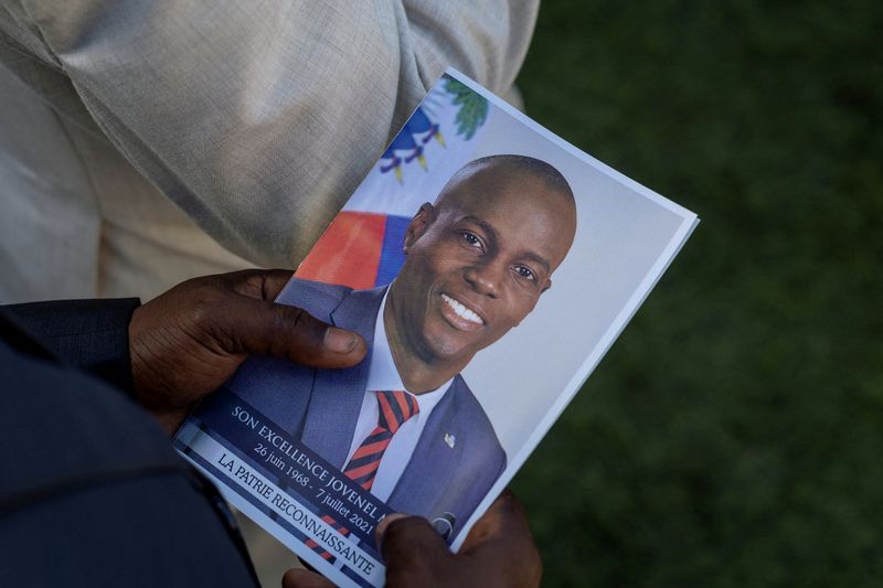 &copy; Reuters. FILE PHOTO: A person holds a photo of late Haitian President Jovenel Moise, who was shot dead earlier this month, during his funeral at his family home in Cap-Haitien, Haiti, July 23, 2021. REUTERS/Ricardo Arduengo/File Photo