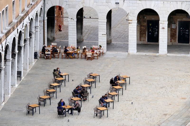 &copy; Reuters. FILE PHOTO: Italians enjoy aperitivo evening drinks sitting down at a bar as much of the country becomes a 'yellow zone', easing coronavirus disease (COVID-19) restrictions allowing bars and restaurants to serve clients at outdoor tables, in Venice, Italy