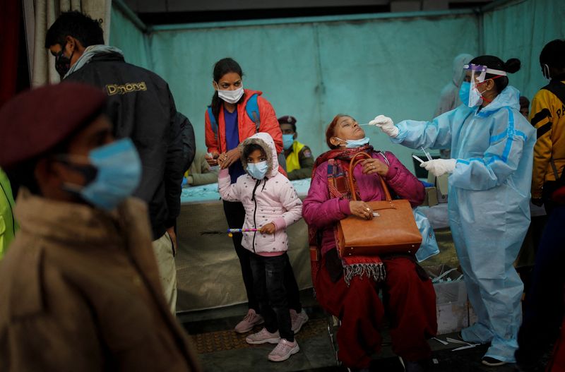 &copy; Reuters. A healthcare worker collects a coronavirus disease (COVID-19) test swab sample from a woman amidst the spread of the disease, at a railway station in New Delhi, India, January 5, 2022. REUTERS/Adnan Abidi