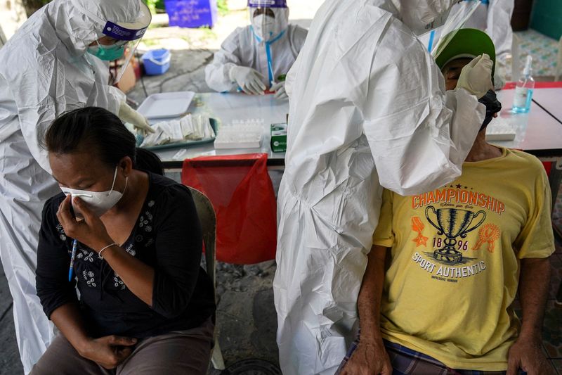 &copy; Reuters. Health workers from Zendai organisation in personal protective equipment (PPE) take swab samples from people for a rapid antigen test amid the coronavirus disease (COVID-19) outbreak, in Bangkok, Thailand, January 5, 2022. REUTERS/Athit Perawongmetha