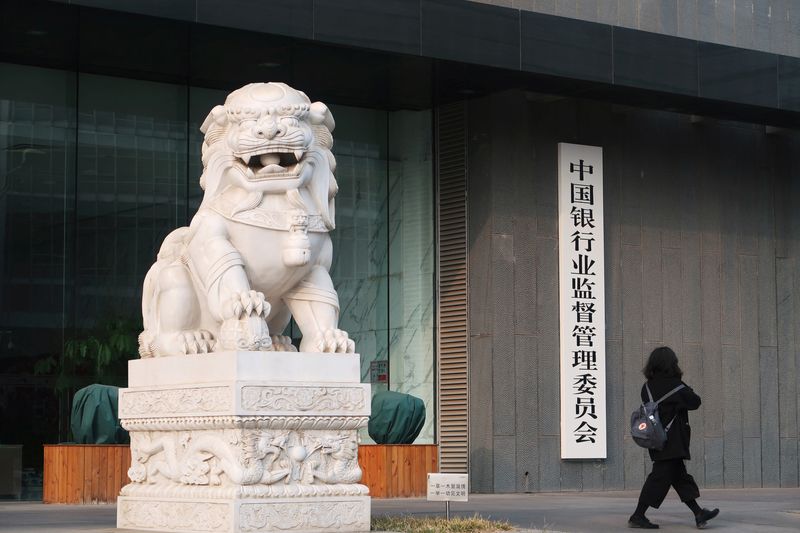 © Reuters. FILE PHOTO: A woman walks past a sign of China Banking Regulatory Commission (CBRC) at its office in Beijing, China March 13, 2018.  REUTERS/Rita Qian