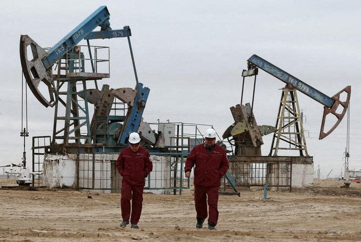 &copy; Reuters. Workers walk as oil pumps are seen in the background in the Uzen oil and gas field in the Mangistau Region of Kazakhstan November 13, 2021. Picture taken November 13, 2021. REUTERS/Pavel Mikheyev