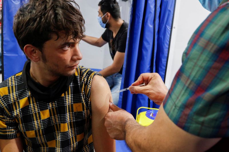 &copy; Reuters. رجل يتلقى لقاحا للوقاية من فيروس كورونا في شاحنة متنقلة للتطعيم في مدينة الصدر بالعراق في العاشر من أغسطس آب 2021. تصوير: أحمد سعد - رويترز