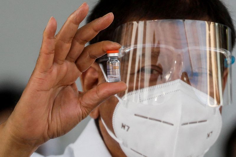 © Reuters. صورة من أرشيف رويترز للرئيس الفلبيني رودريجو دوتيرتي يحمل قنينة من لقاح مضاد لفيروس كورونا.