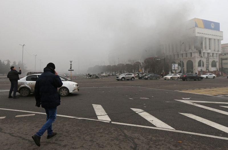 © Reuters. مواطنون يمرن قرب بناية في ألما اتا قال تلفزيون قازاخستان إن النيران أضرمت فيها خلال احتجاجات بسبب ارتفاع أسعار الوقود يوم الخميس. تصوير بافيل ميخييف- رويترز.