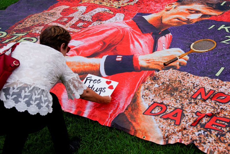 &copy; Reuters. A woman places a 'Free hugs' sign on a banner of Serbian tennis player Novak Djokovic outside the Park Hotel, where the star athlete is believed to be held while he stays in Australia, in Melbourne, Australia, January 7, 2022. REUTERS/Sandra Sanders
