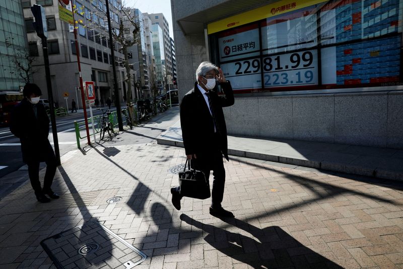 &copy; Reuters. FILE PHOTO: People wearing surgical masks walk past a screen showing Nikkei index outside a brokerage in Tokyo, Japan February 3, 2020. REUTERS/Kim Kyung-Hoon