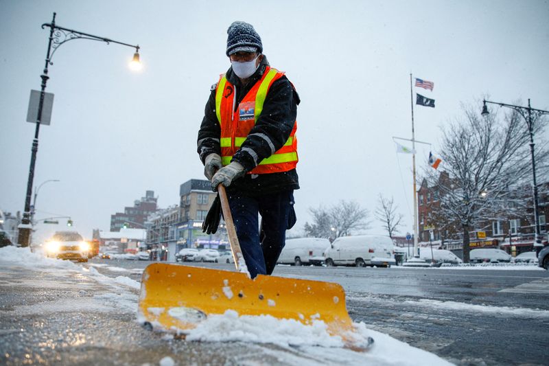 &copy; Reuters. A New York City Transit worker clears snow from a sidewalk for the morning commute outside a subway station during a snow storm in Brooklyn, New York City, New York, U.S., January 7, 2022. REUTERS/Brendan McDermid