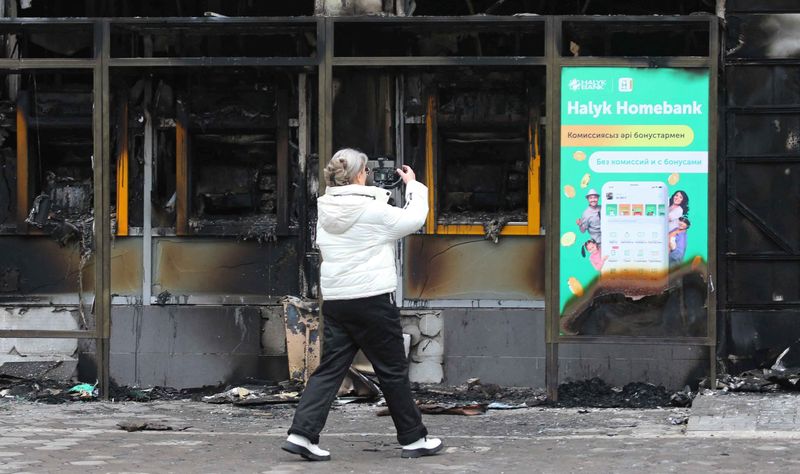 &copy; Reuters. امرأة تصور مبنى تم حرقه خلال احتجاجات حاشدة بسبب زيادة أسعار الوقود في ألما أتا يوم الأحد. تصوير: بافيل ميخييف - رويترز