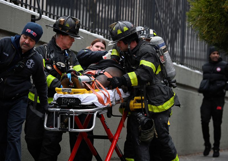 © Reuters. Emergency personnel from the FDNY provide medical aid as they respond to an apartment building fire in the Bronx borough of New York City, U.S., January 9, 2022.  REUTERS/Lloyd Mitchell